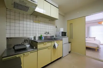 a kitchen with yellow appliances and a bed in a room at #4 -\u30a8\u30af\u30bb\u30eb\u6a4b\u7acb102- Entire Unit in Tokyo
