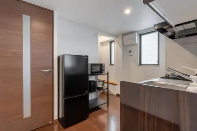 a kitchen with a black refrigerator and a sink at \u4ee3\u3005\u6728\u4e0a\u539f in Tokyo