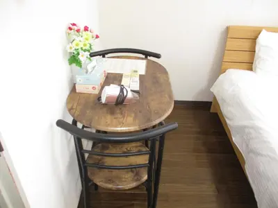a small table with a vase of flowers on it next to a bed at \u30e9\u30a4\u30aa\u30f3\u30ba\u30de\u30f3\u30b7\u30e7\u30f3\u9053\u7384\u5742c in Tokyo