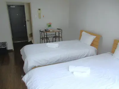 a room with two beds and a table with a chair at \u30e9\u30a4\u30aa\u30f3\u30ba\u30de\u30f3\u30b7\u30e7\u30f3\u9053\u7384\u5742c in Tokyo