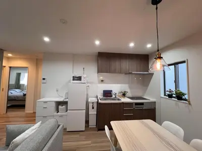 a kitchen with a white refrigerator and a table and chairs at \u62bc\u4e0aSkytree Oshiage Hostel-KT0032 in Tokyo