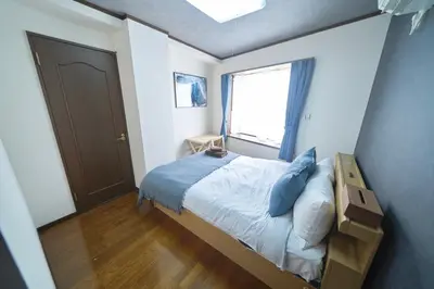 a bedroom with a bed with blue pillows and a window at FINOA Residential Suite Kamata in Tokyo