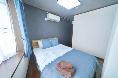 a small bedroom with a bed with blue pillows at FINOA Residential Suite Kamata in Tokyo