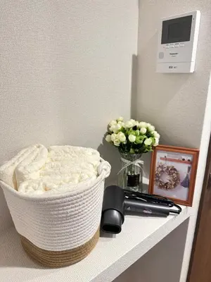 a white basket on a shelf with a phone and flowers at \u6da9\u8c37\u6c11\u5bbf in Tokyo