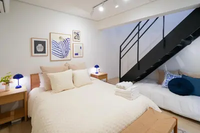 a bedroom with a large white bed and a staircase at Ken's Place Omotesando in Tokyo