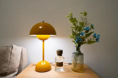 a table with a lamp and a vase of flowers at Ken's Place Omotesando in Tokyo