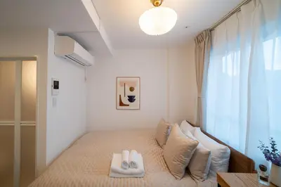 a small bedroom with a bed with white pillows at Ken's Place Omotesando in Tokyo