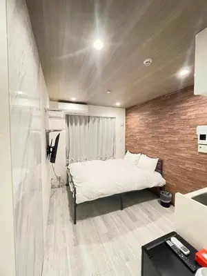a bedroom with a white bed and a brick wall at fukuhana \u6771\u65b0\u5bbf2 in Tokyo