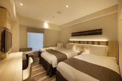 a hotel room with two beds and a television at Hotel Sunroute Ginza in Tokyo