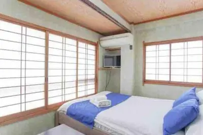 a bedroom with a bed with blue pillows and windows at Sky sweet home in Tokyo
