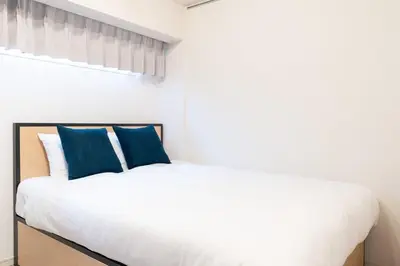 a bedroom with a white bed with blue pillows at PL Park Lane\u767d\u91d1\u9ad8\u8f2a in Tokyo
