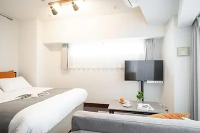 a bedroom with a bed and a tv and a couch at PL Park Lane\u767d\u91d1\u9ad8\u8f2a in Tokyo