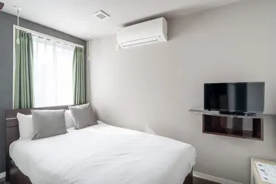 a bedroom with a bed with a tv on the wall at Apartment\u5c0f\u77f3\u5ddd\u5f8c\u697d\u5712 in Tokyo