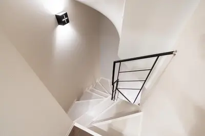 a spiral staircase with a light on the wall at Apartment\u5c0f\u77f3\u5ddd\u5f8c\u697d\u5712 in Tokyo