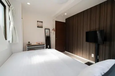 a bedroom with a large bed and a flat screen tv at MX House - Cozy APT Stay in Ikebukuro Tokyo, with Direct Access to Shinjuku & Shibuya in Tokyo
