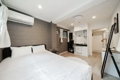 a bedroom with a white bed and a kitchen at MX House - Cozy APT Stay in Ikebukuro Tokyo, with Direct Access to Shinjuku & Shibuya in Tokyo