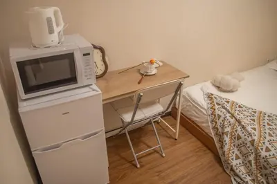a microwave on top of a refrigerator next to a bed at Nakano106,Nakano Broadway,Shinjuku 1 stop in Tokyo