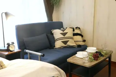 a blue couch with pillows and a table in a room at Gaia Kabukicho 301 \u30ac\u30a4\u30a2\u6b4c\u821e\u4f0e\u753a in Tokyo