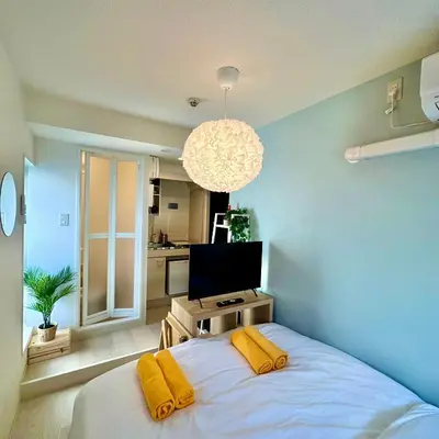 a bedroom with a bed with yellow pillows and a television at PLAZA SINJUKU Cozy Mansion in Tokyo