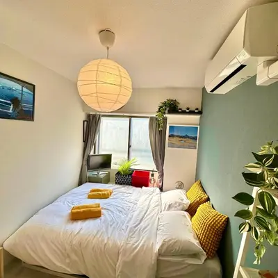 a bedroom with a white bed with yellow pillows at PLAZA SINJUKU Cozy Mansion in Tokyo