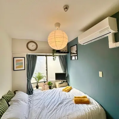 a bedroom with a large white bed with a blue wall at PLAZA SINJUKU Cozy Mansion in Tokyo