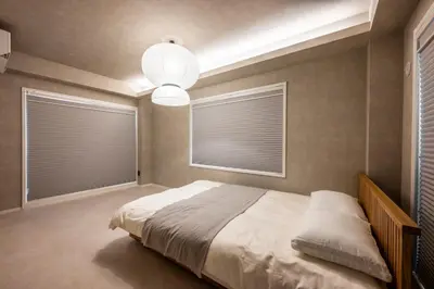 a bedroom with a bed and two windows with blinds at WABI & GIVE Nakano Araiyakushi in Tokyo