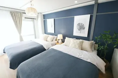 two beds in a bedroom with blue walls at \u30aa\u30b0\u30e9\u30d3\u30eb 403 in Tokyo