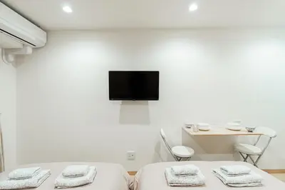 a room with two beds and a tv on the wall at Kiwami Hotel Shinjuku in Tokyo