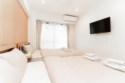 two beds in a room with a tv on the wall at Kiwami Hotel Shinjuku in Tokyo