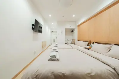 two beds in a room with a tv on the wall at Kiwami Hotel Shinjuku in Tokyo