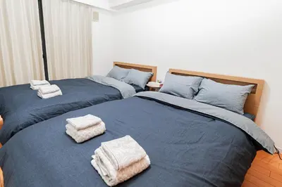 two beds with towels on them in a bedroom at Mio Hotel Shinjuku Tokyo in Tokyo