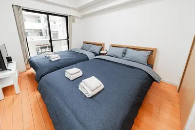 two beds in a bedroom with blue sheets and towels at Mio Hotel Shinjuku Tokyo in Tokyo