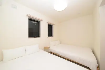 two beds in a small room with two windows at NYHotel 1 \u65b0\u5bbf2\u968e\u5efa\u30664\u5ba41\u30d0\u30b9\u30eb\u30fc\u30e01\u30b7\u30e3\u30ef\u30fc2\u30c8\u30a4\u30ec in Tokyo