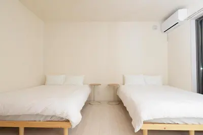 two beds in a room with white walls at NYHotel 1 \u65b0\u5bbf2\u968e\u5efa\u30664\u5ba41\u30d0\u30b9\u30eb\u30fc\u30e01\u30b7\u30e3\u30ef\u30fc2\u30c8\u30a4\u30ec in Tokyo