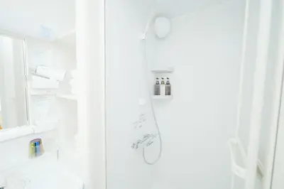 a white bathroom with a shower and a refrigerator at \u6771\u4eac\u30ea\u30ea\u30a2\u30eb\u30db\u30c6\u30eb0501 in Tokyo