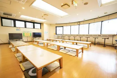 a classroom with tables and chairs and a projection screen at Capsule Inn Otsuka in Tokyo