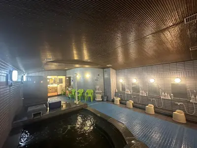 a room with a pool of water with green chairs at Capsule Inn Otsuka in Tokyo
