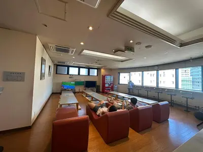 a group of people sitting on a couch in a room at Capsule Inn Otsuka in Tokyo