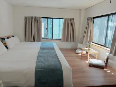 a bedroom with a large bed and two windows at Softlight Inn Asakusa Tokyo in Tokyo