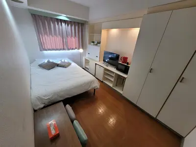 a small room with a bed and a desk with a television at Urban Stage Okubo in Tokyo