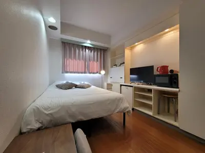 a bedroom with a bed and a desk with a microwave at Urban Stage Okubo in Tokyo