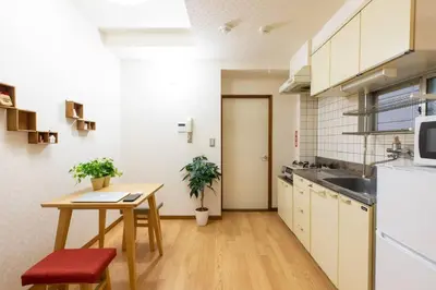 a kitchen with a wooden table and a kitchen with white appliances at Minimalism Hotel Sumida 1 in Tokyo