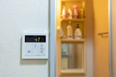 a clock on a wall next to a shelf with bottles at Minimalism Hotel Sumida 2 in Tokyo