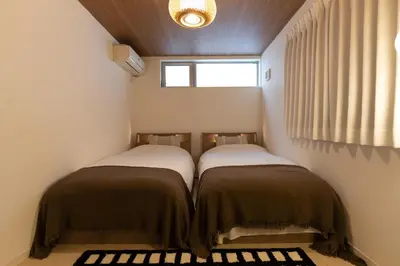 two beds in a small room with a window at Hotel Beswe in Tokyo