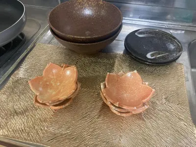 three oysters sitting on top of a counter next to a bowl at B&K Numabukuro in Tokyo