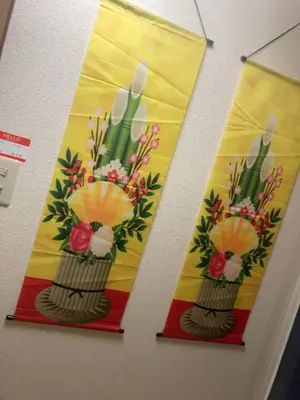 two banners hanging on a wall with flowers in a vase at B&K Numabukuro in Tokyo