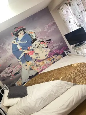 a bedroom with a painting of a woman on a wall at B&K Numabukuro in Tokyo