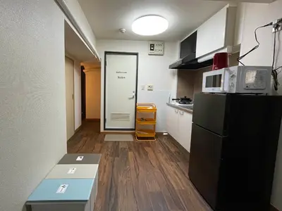a small kitchen with a black refrigerator and a door at JK House in Tokyo