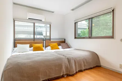 a bedroom with a large bed with yellow pillows at \u4e0a\u5317\u6ca2\u6238\u5efa\u3066 in Tokyo