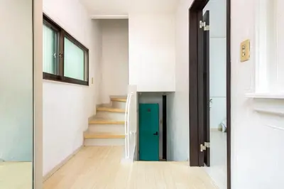 a hallway with a green door and stairs at \u4e0a\u5317\u6ca2\u6238\u5efa\u3066 in Tokyo